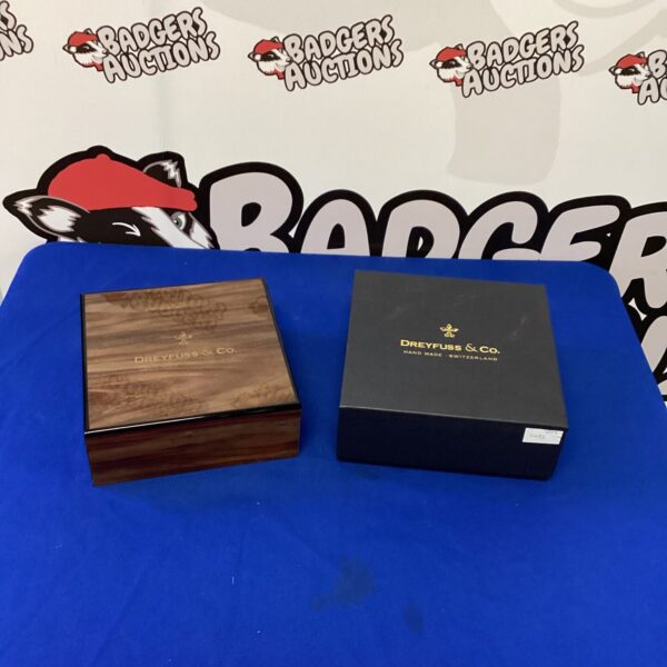 Front view of a Dreyfuss & Co wooden watch box on a patterned surface.