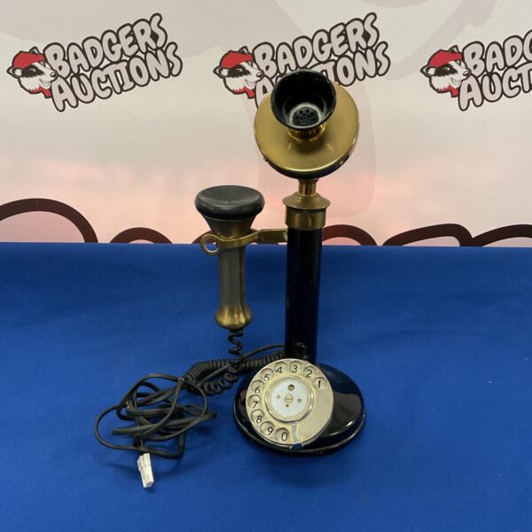 Vintage candlestick telephone with brass base and rotary dial.
