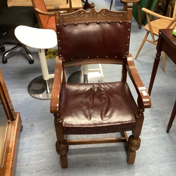 Antique acorn chair with carved wood details and brown upholstery.