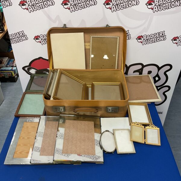 Vintage travel case open with empty photo frames inside.
