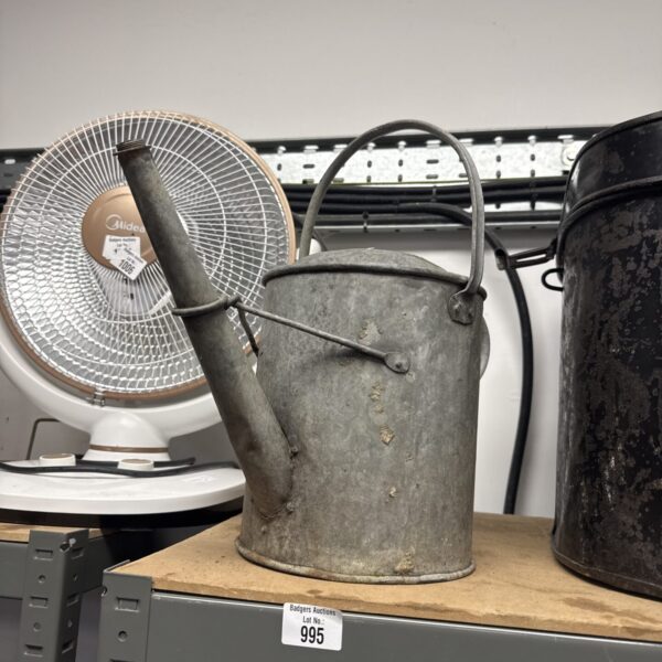 Vintage galvanised watering can with a fan in the background.