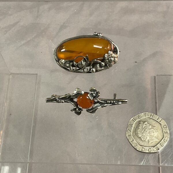 Silver Art Nouveau brooch with amber and floral details.