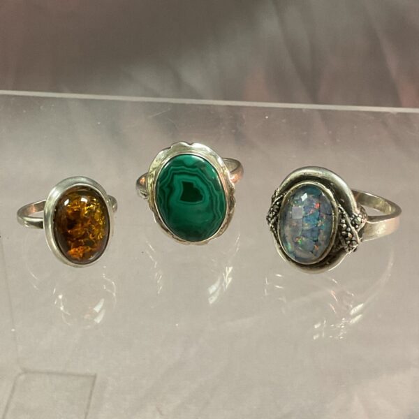 Silver rings set with malachite, amber, and opal gemstones.