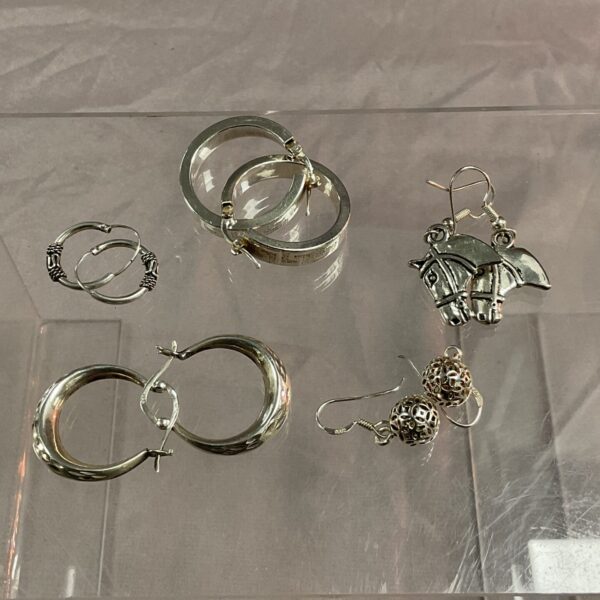 Close-up of a lot of 925 silver earrings with varied designs.
