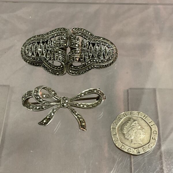 Vintage silver marcasite bow brooch and earring set on display.