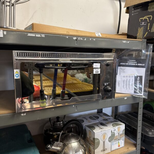 Front view of stainless steel Dometic built-in grill on a shelf.