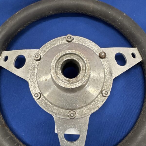Front view of a vintage steering wheel with leather grip.