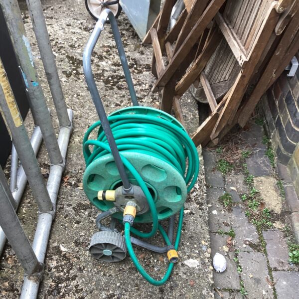 Green garden hose reel with hose coiled for outdoor watering.