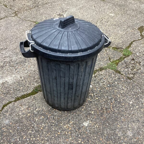 Black plastic dust bin with a secure lid for outdoor waste storage.