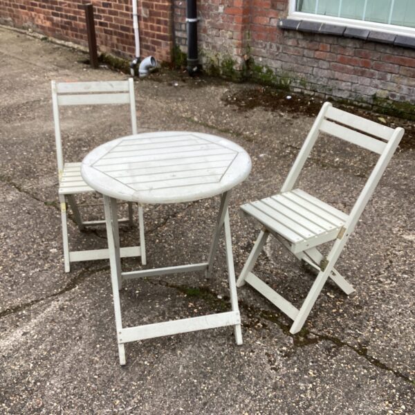 Vintage garden table and two folding chairs in a garden setting.