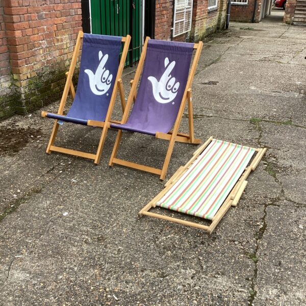 Lot of three vintage striped deck chairs in a garden setting.