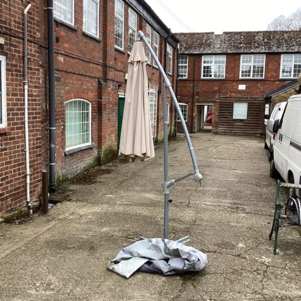Large garden parasol with base and protective cover outdoors.