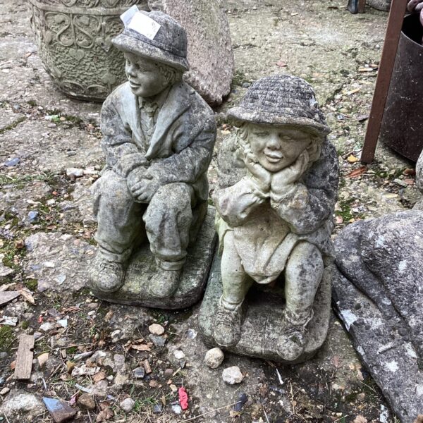 Vintage garden boy and girl ornaments in a garden setting.