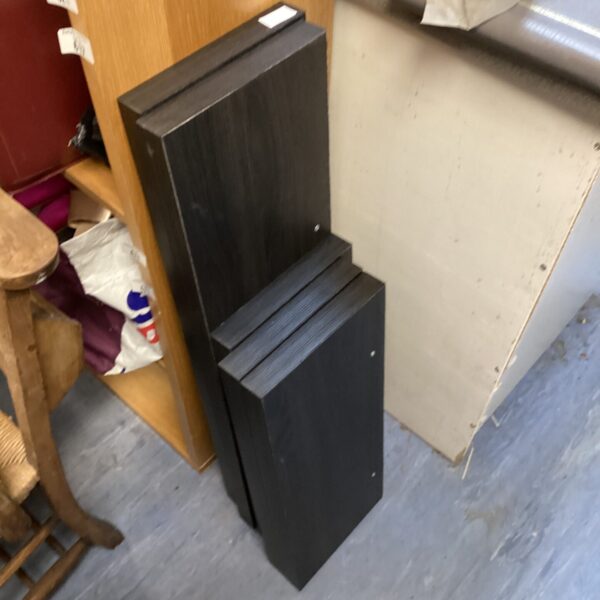 Set of five black floating shelves stacked together.