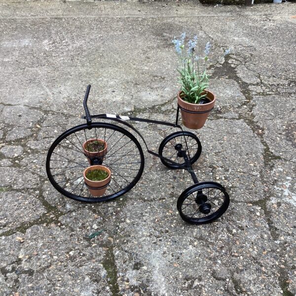 Black metal bike plant pot holder with a potted plant.