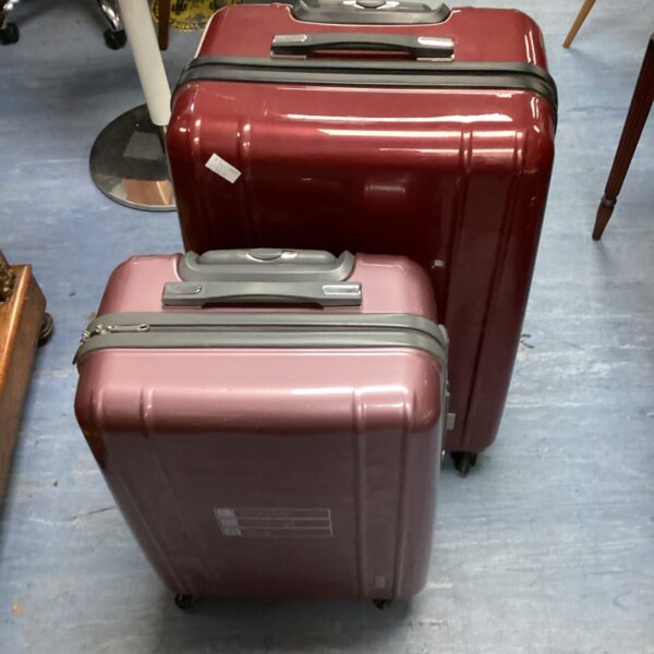 Pink and maroon hard case suitcases with wheels for travel.