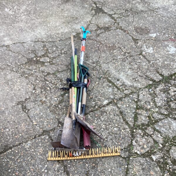 Bundle of used garden tools including a spade and rake.