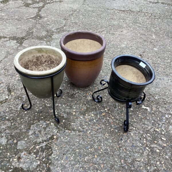 Collection of three terracotta garden pots with metal stands.