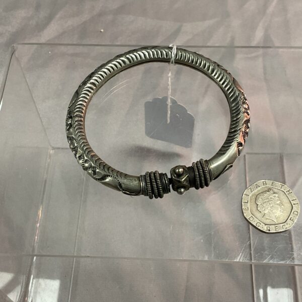 Intricate silver Indian bangle with detailed tribal design.