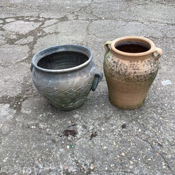 Pair of weathered terracotta garden urns in a garden setting.