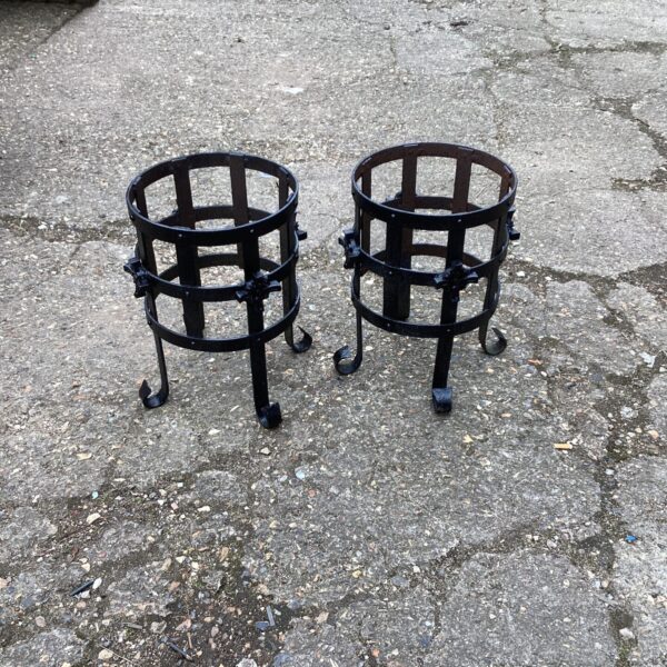 Two weathered metal garden plant pot stands for displaying plants.