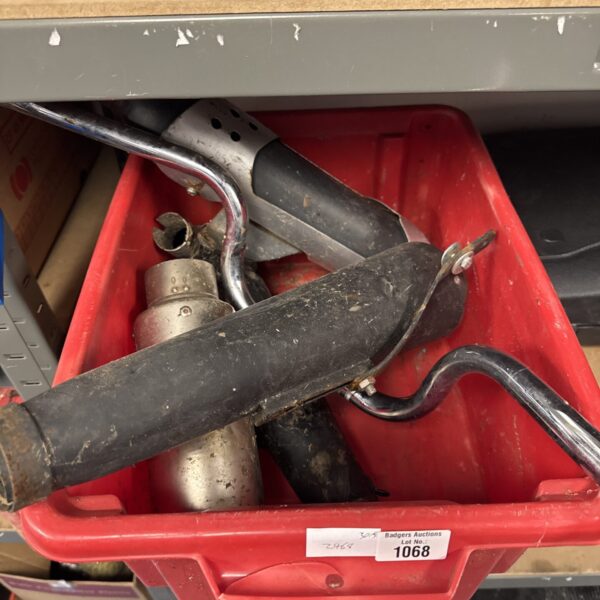 Assorted motorcycle parts including silencers and handlebars in a lot.
