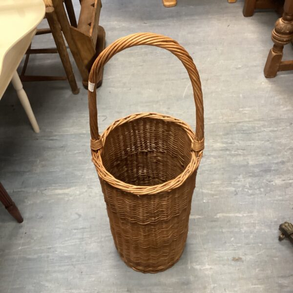 Large wicker log basket for firewood storage near a fireplace.