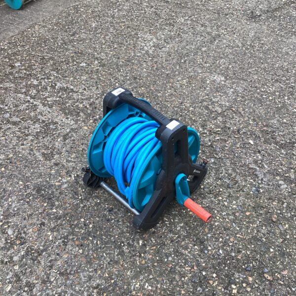 Close-up of a plastic garden hose reel with a green hose.