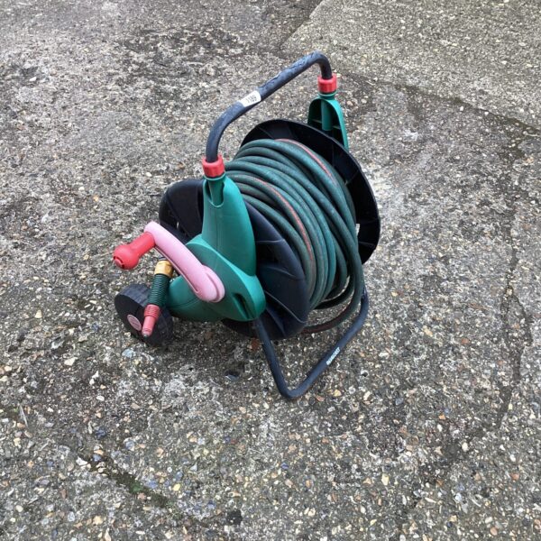 Green garden hose neatly wound on a metal reel.
