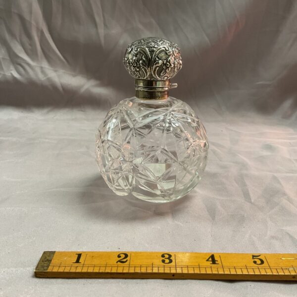 Antique silver lidded perfume bottle with faceted crystal body.