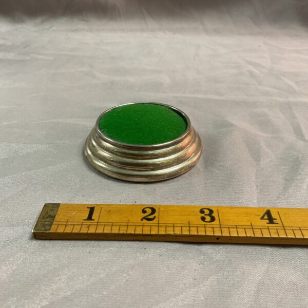Antique silver pin cushion with measuring tape for scale.
