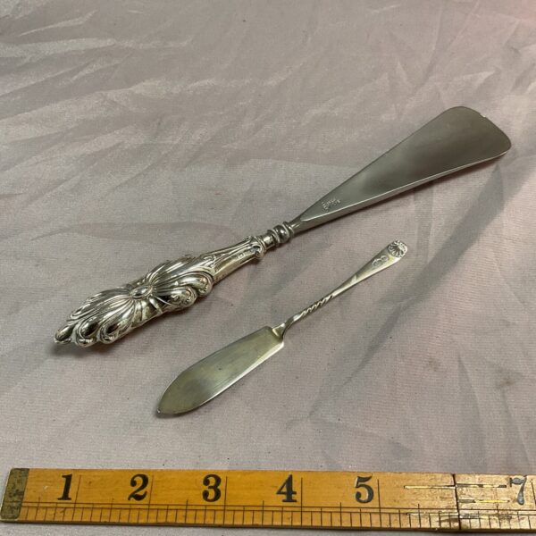 Antique silver shoehorn and butterknife set with ornate handles.