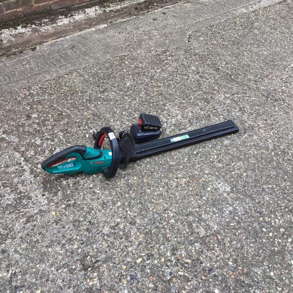 Bosch cordless hedge trimmer with charger for garden maintenance.