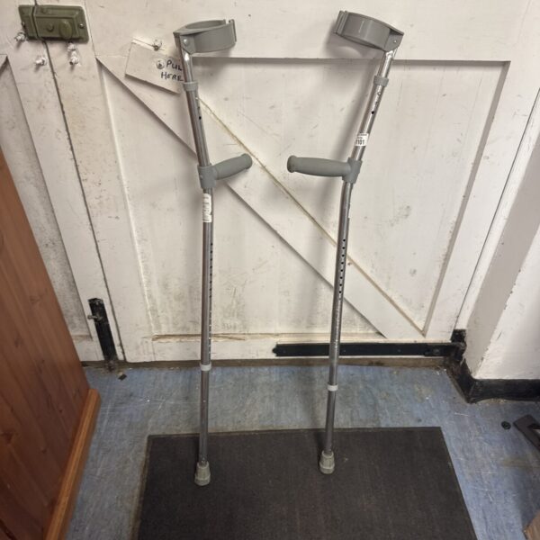 Pair of silver Trulife extendable crutches against a wall.