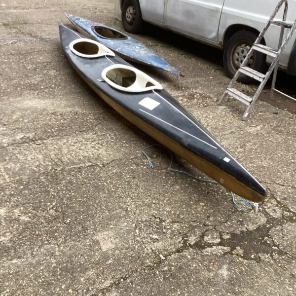 Exterior view of a two-person canoe on a paved surface.