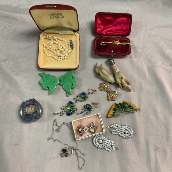 Assortment of vintage jewellery on a tray, including brooches and earrings.