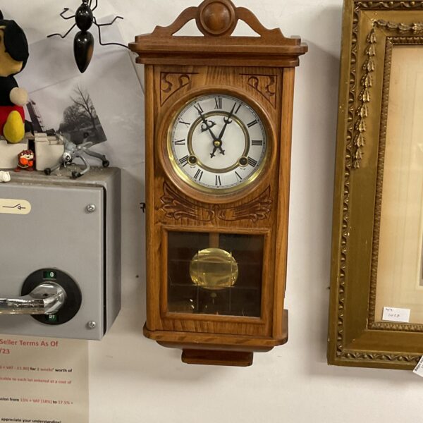 Vintage teak wall clock with enamel face, a classic timepiece.