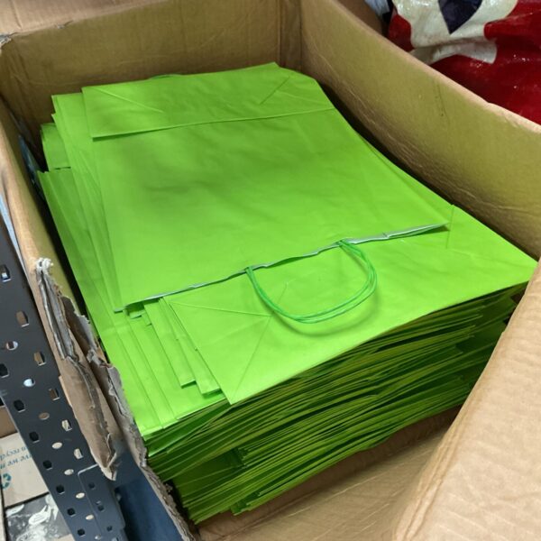 Bulk lot of vibrant green paper carrier bags for retail use.