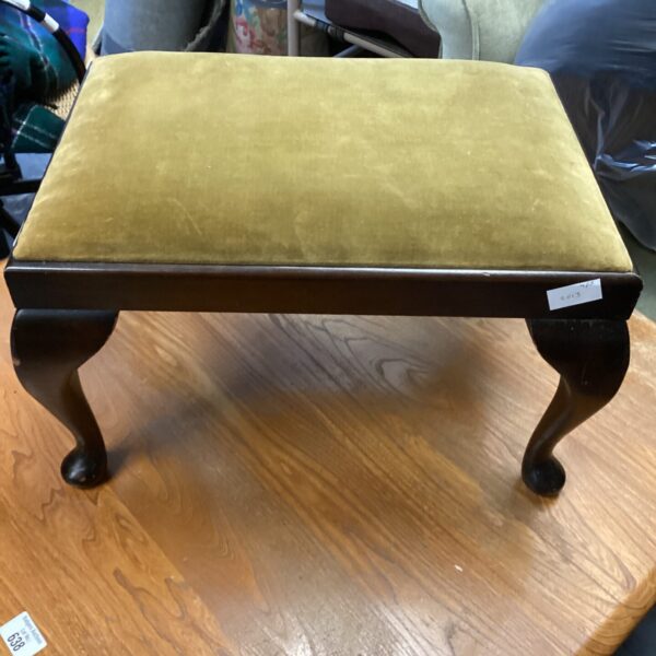 Vintage footstool with patterned upholstery and carved wooden legs.