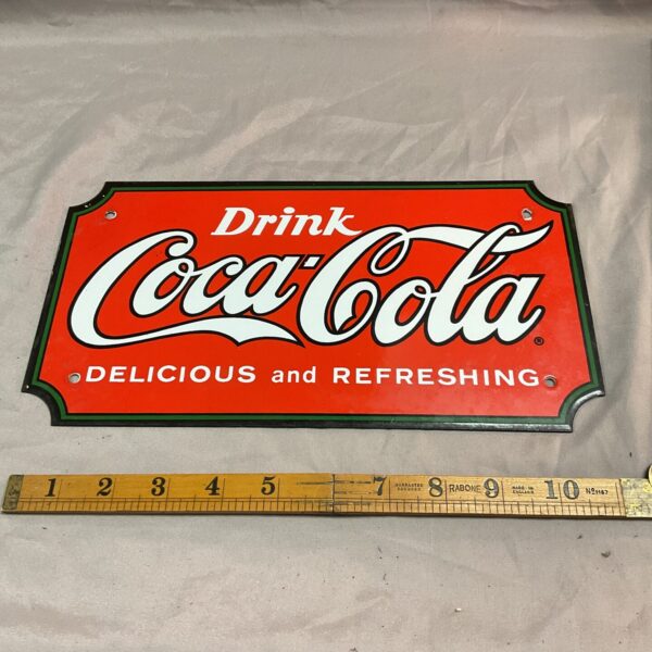 Vintage Coca Cola enamel sign with classic branding.