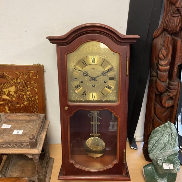 Vintage Ams mechanical wall clock with pendulum and Roman numerals.