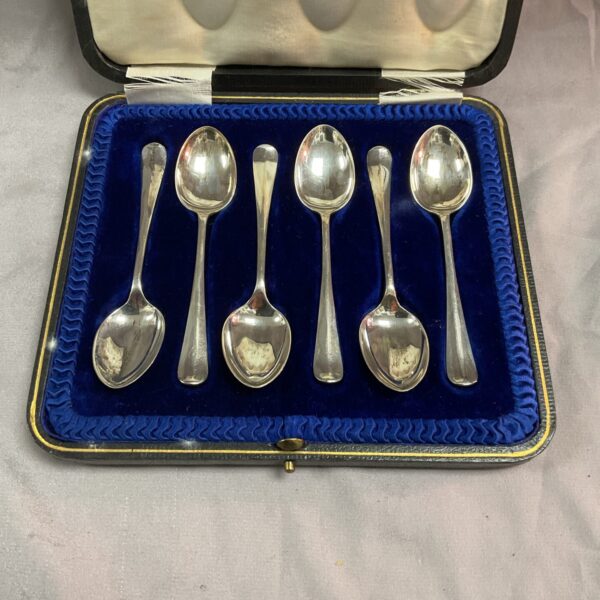 Vintage silver rat tail teaspoons presented in a blue case.