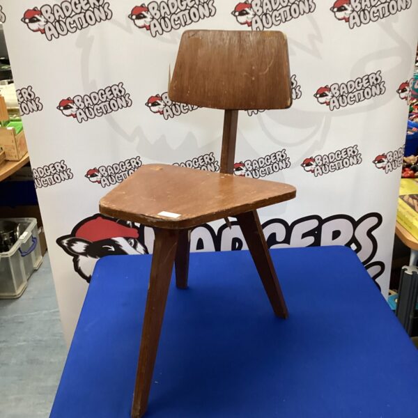 Vintage three-legged wooden childrens chair, side view.