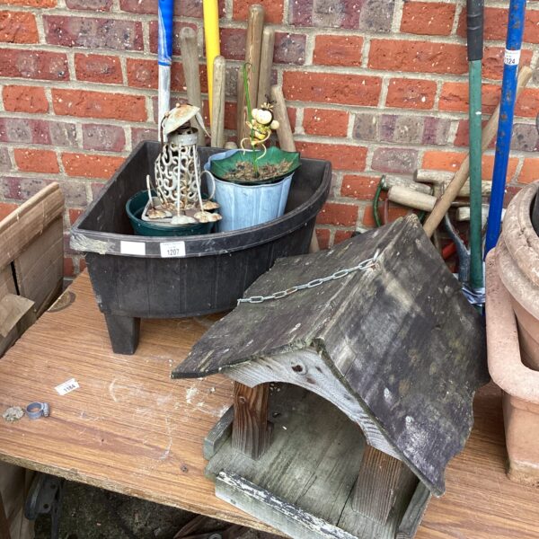 Rustic wooden bird table in a garden setting with other items.