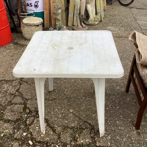 White plastic garden table in an outdoor setting.