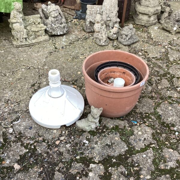 Robust patio parasol base with garden pots in background.
