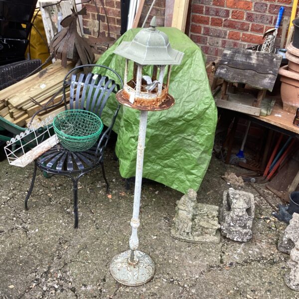 Vintage metal bird table in a garden setting.