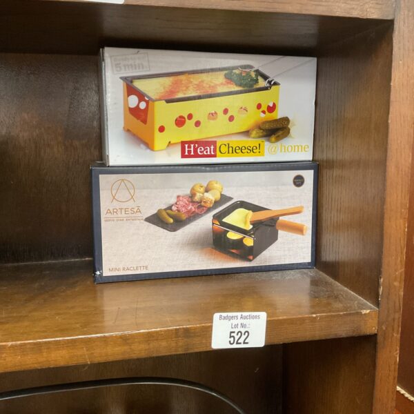 Two mini cheese raclette sets for melting cheese at the table.