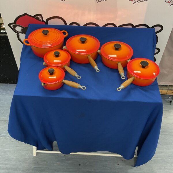Vibrant orange Le Creuset cookware set on a table.