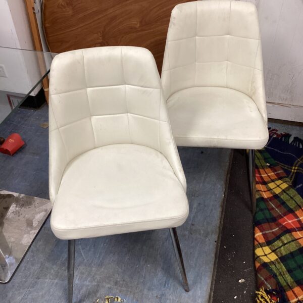 Two white leather reception chairs with tapered legs.